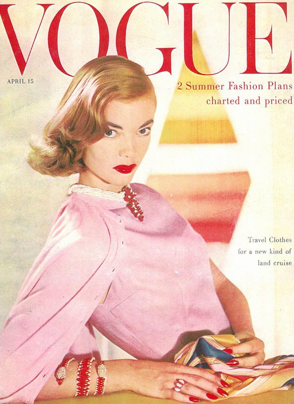 Front cover of a Vogue magazine with a model posing in a pink blouse.