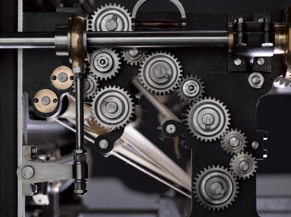 Close up of many interlocking silver cogs inside a machine.