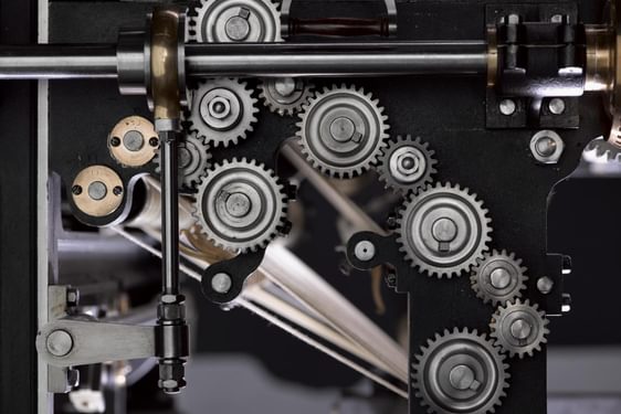 Close up of many interlocking silver cogs inside a machine.