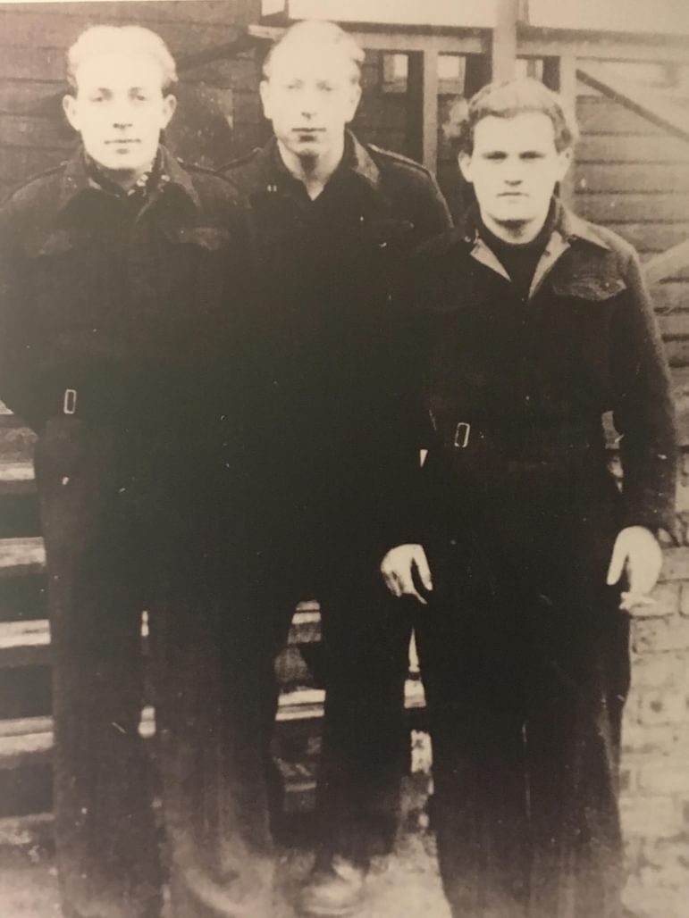 A black and white photograph of three prisoners of war in dark clothing.