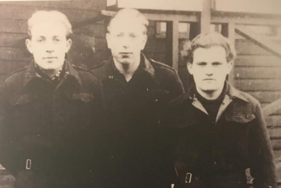A black and white photograph of three prisoners of war in dark clothing.