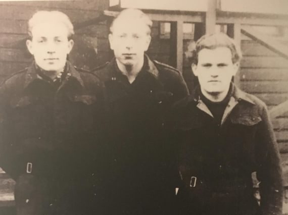 A black and white photograph of three prisoners of war in dark clothing.