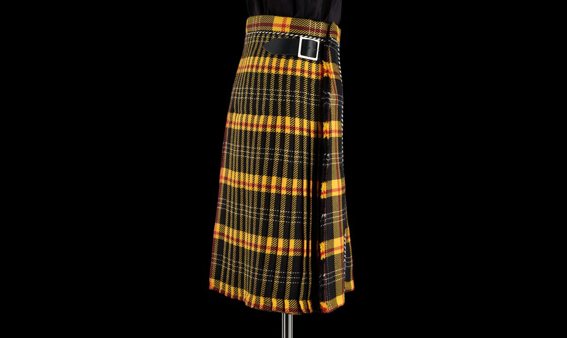 A yellow and black tartan kilt with a leather buckle fastening at the side.