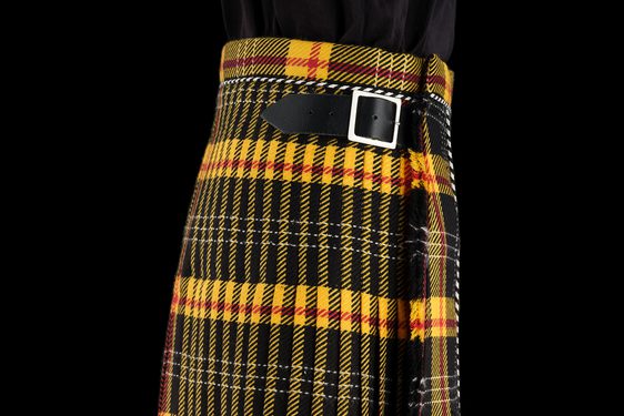 A yellow and black tartan kilt with a leather buckle fastening at the side.