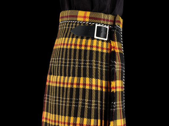 A yellow and black tartan kilt with a leather buckle fastening at the side.