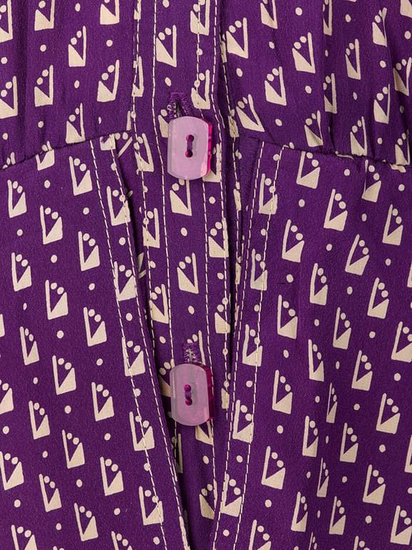 Detail of a patterned purple dress with purple rectangular buttons.