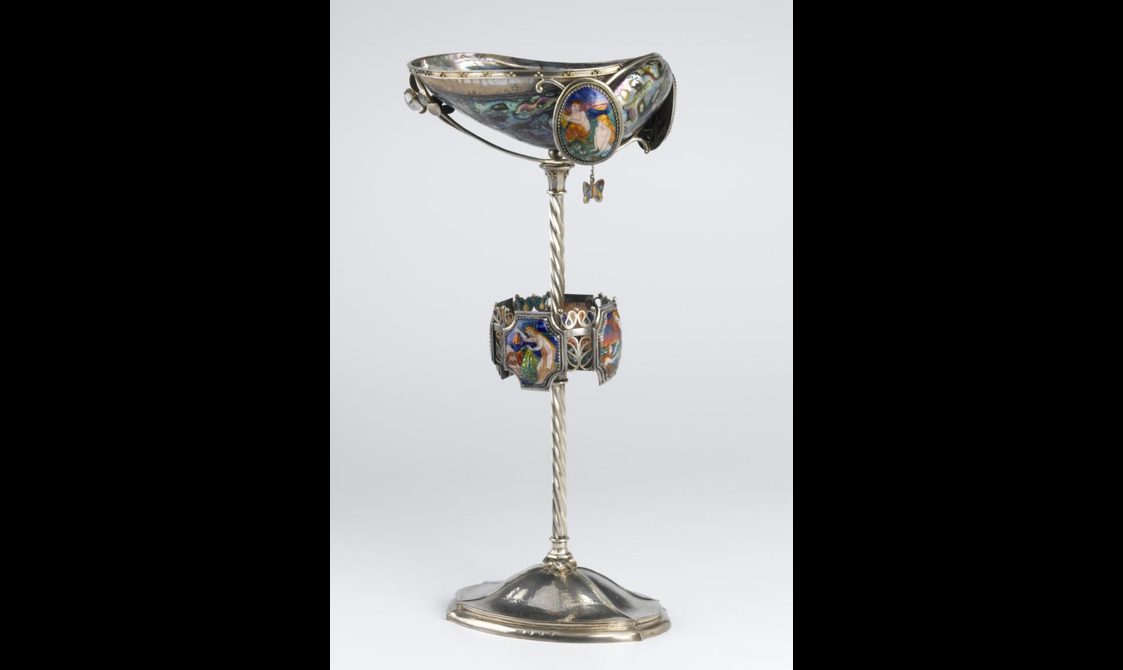 An elaborate chalice made of silver, colourful enameled panels, and shells with a marbled surface. It has a decorative cup sitting on a long silver stem.