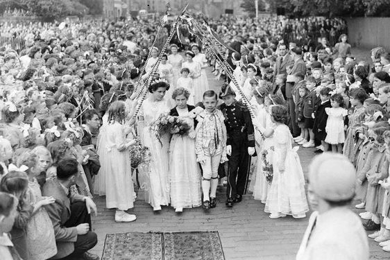 A gala day queen and her party made up of children walk through a crowd of hundreds of children