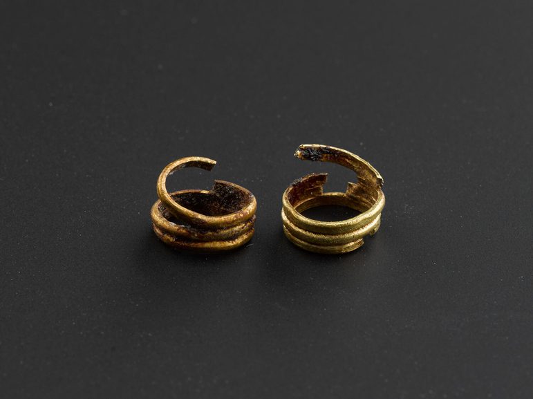A pair of hoop gold earrings against a black background