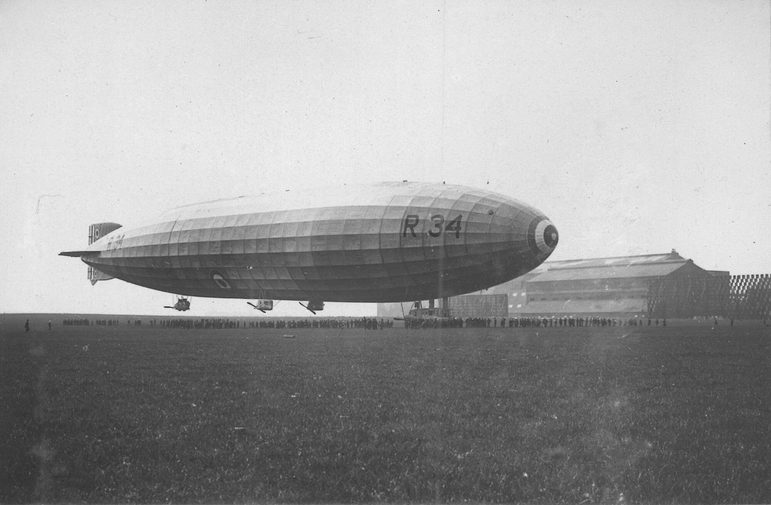 A black and white image of a blimp like airship at an airfield.