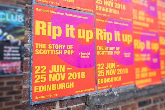 Posters on a brick wall advertising the 'Rip it Up' exhibition.