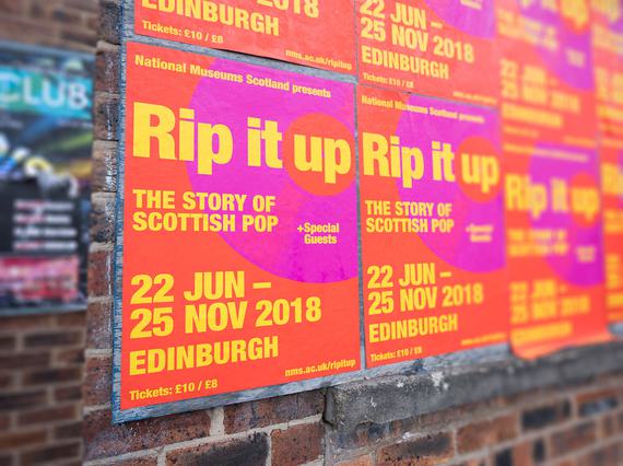 Posters on a brick wall advertising the 'Rip it Up' exhibition.