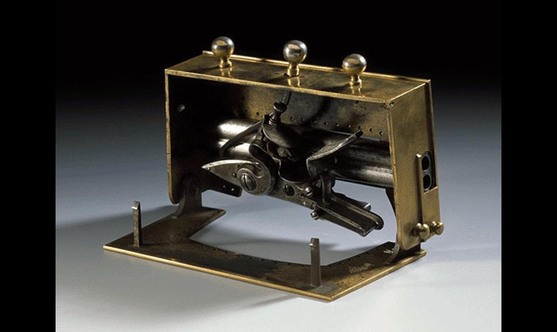 Side view of an open brass sporran clasp with hidden pistols inside.