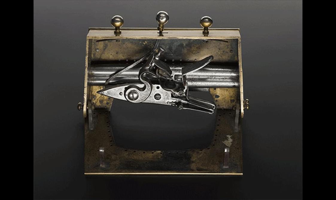 Front view of an open brass sporran clasp with hidden pistols inside.