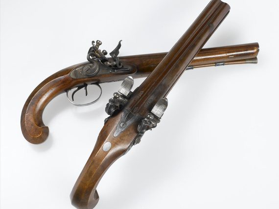 Two wood and metal pistols set against a white background. One pistol is laid on a side and the other placed on top.