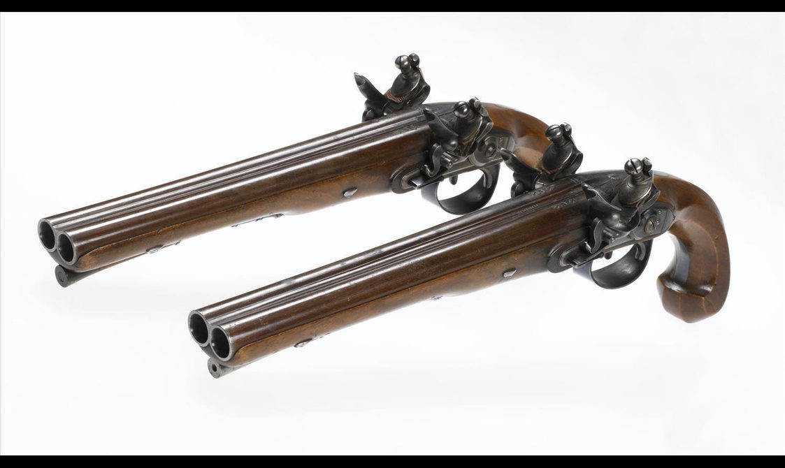 Two wood and metal pistols against a white background placed on an angle facing the left hand side.