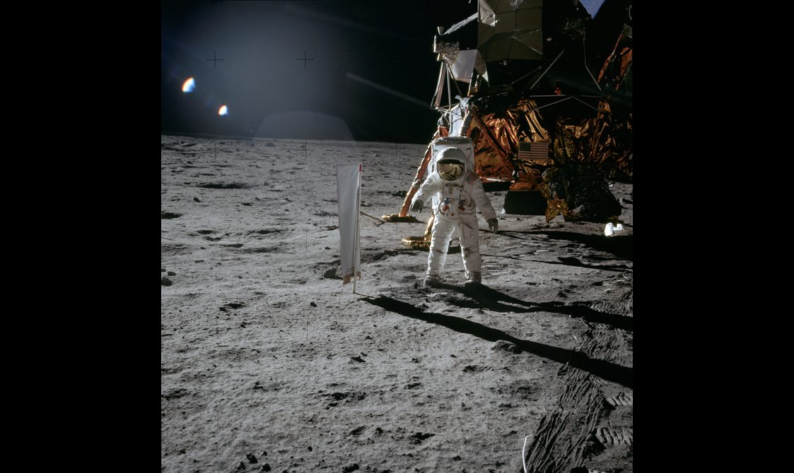 An astronaut on the moon's surface with the space craft in the background.