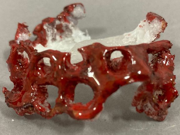 A close up of a piece of red glass in a twisted shape