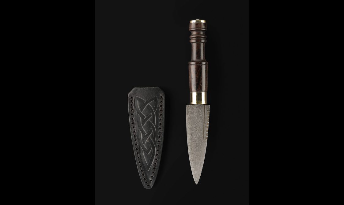 A small knife with a wooden handle and a leather sheath.