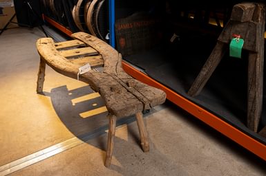 Sheep shearing redwood stool with four legs and one side more narrow than the other.