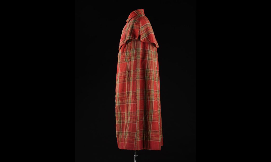 Side view of a mannequin wearing a long red tartan cloak