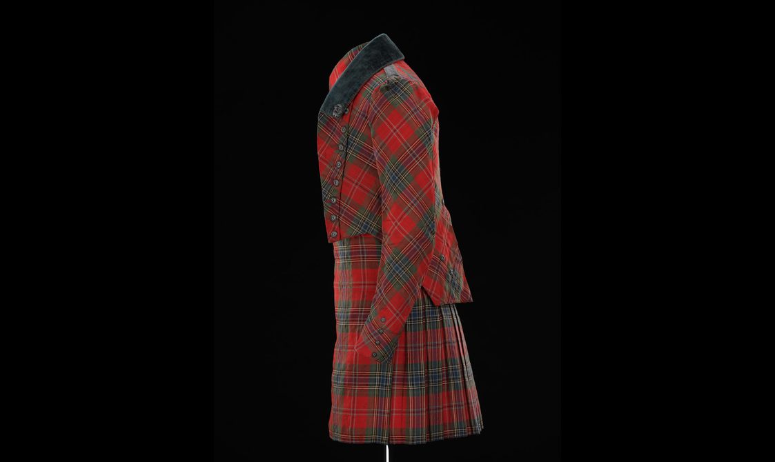 Side view of a mannequin wearing a red tartan kilt with a matching short jacket.