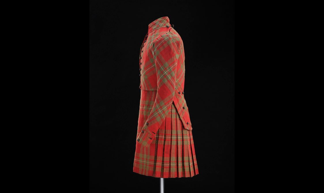 Side view of a mannequin wearing a red tartan kilt with matching jacket.