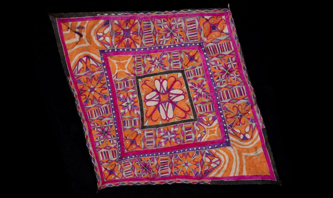 A pink, orange, and white textile laid flat with detailed patterns.