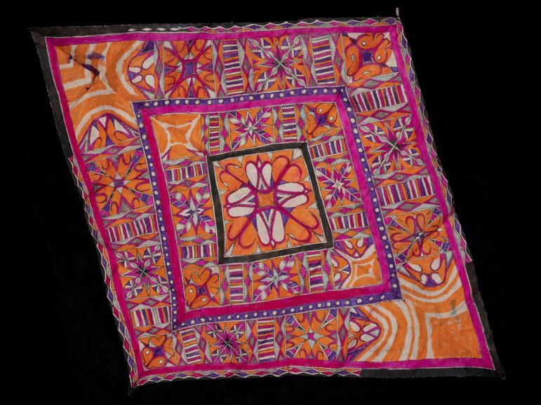 A pink, orange, and white textile laid flat with detailed patterns.
