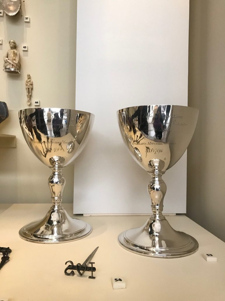 Two silver chalices with writing inscribed on the cup's surface