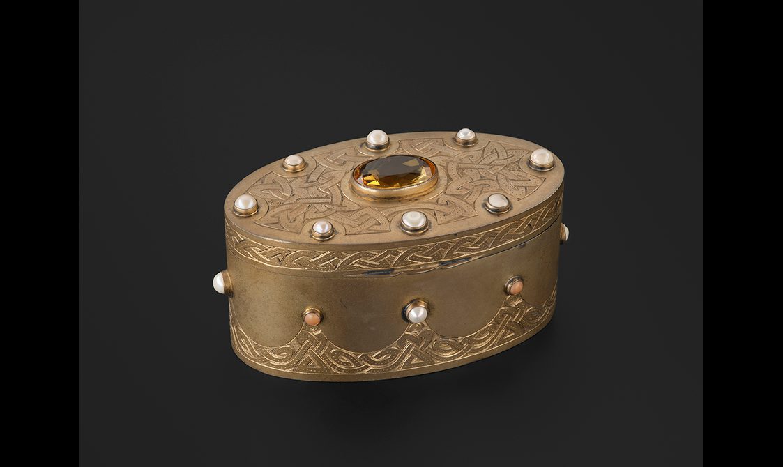 A silver gilt oval box. It's decorated with Scottish pearls around the side and on the edge of the lid. A yellow cairngorm fetures in the middle of the lid.