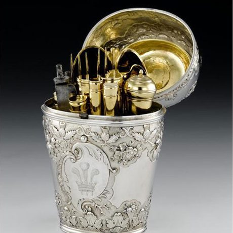 A highly decorated silver object with an open lid which shows various gold objects.
