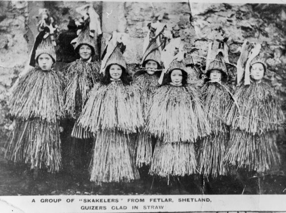 A black and white photograph of women dressed in tall coned decorative hats and flowing, straw like tops and skirts.