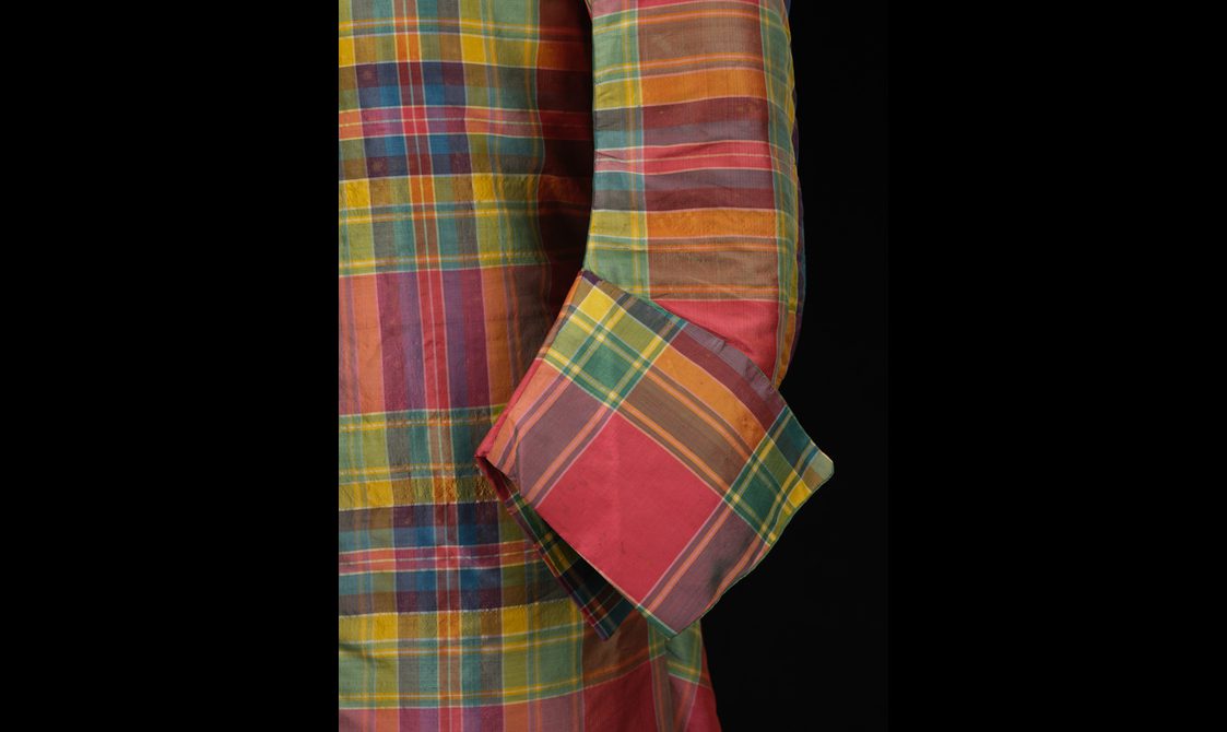 Detail of a red, green, and yellow silk tartan coat with a large turned up cuff.