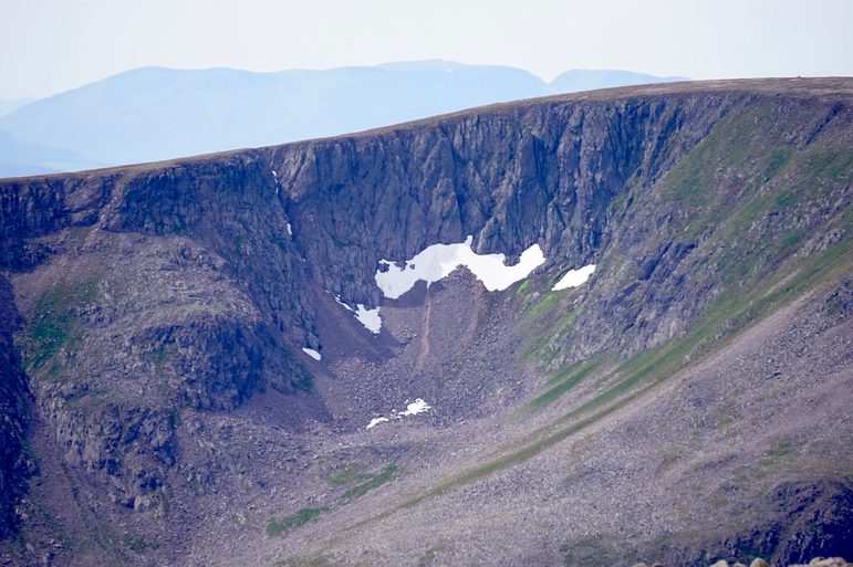 A crater on a mountain with patches of snow.