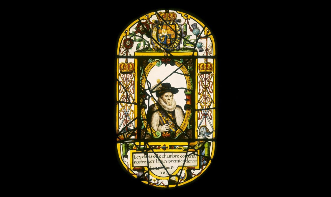 An elaborate stained glass window of a king wearing a ruffled collar and black feathered hat. He is surrounded by flowers, royal crests, and text.