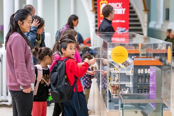 Young person points at a model of the museum made from Lego.