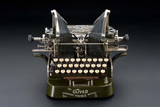 Green mechanical typewriter from the early 1900s with white keys. It says 'The Oliver No. 3, Standard Visible Writer' on the front.
