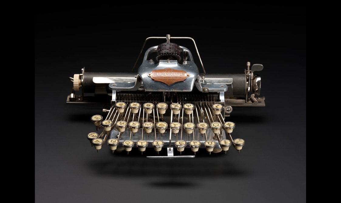A sleek black typewriter with cream-coloured keys against a dark grey background.