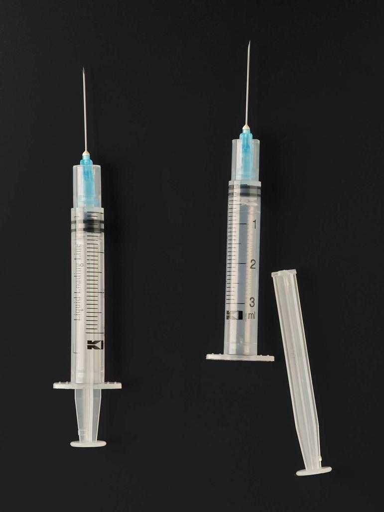 Two plastic syringes with needles. The syringe on the right has its plunger removed.