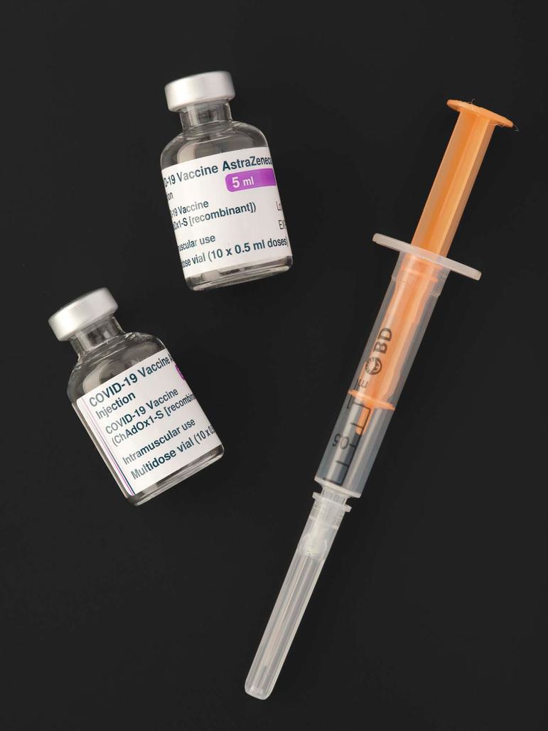 A syringe and two glass vials containing the COVID-19 AstraZeneca vaccine.