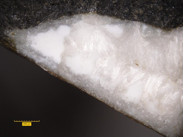 A piece of white rock with a slightly crystallised surface against a black background