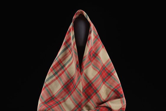 A mannequin wearing a red and cream tartan shawl.