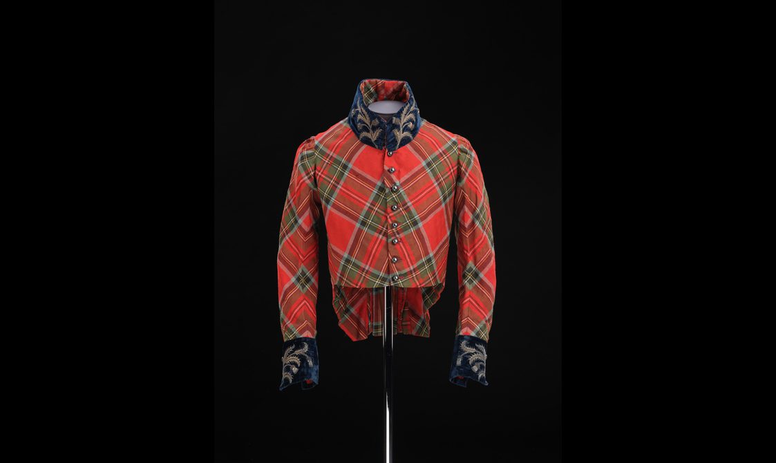 A mannequin wearing a red tartan jacket with navy velvet details