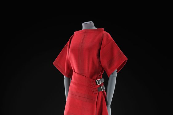 A mannequin wearing a red top and red kilt skirt with a subtle tartan pattern