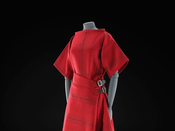 A mannequin wearing a red top and red kilt skirt with a subtle tartan pattern