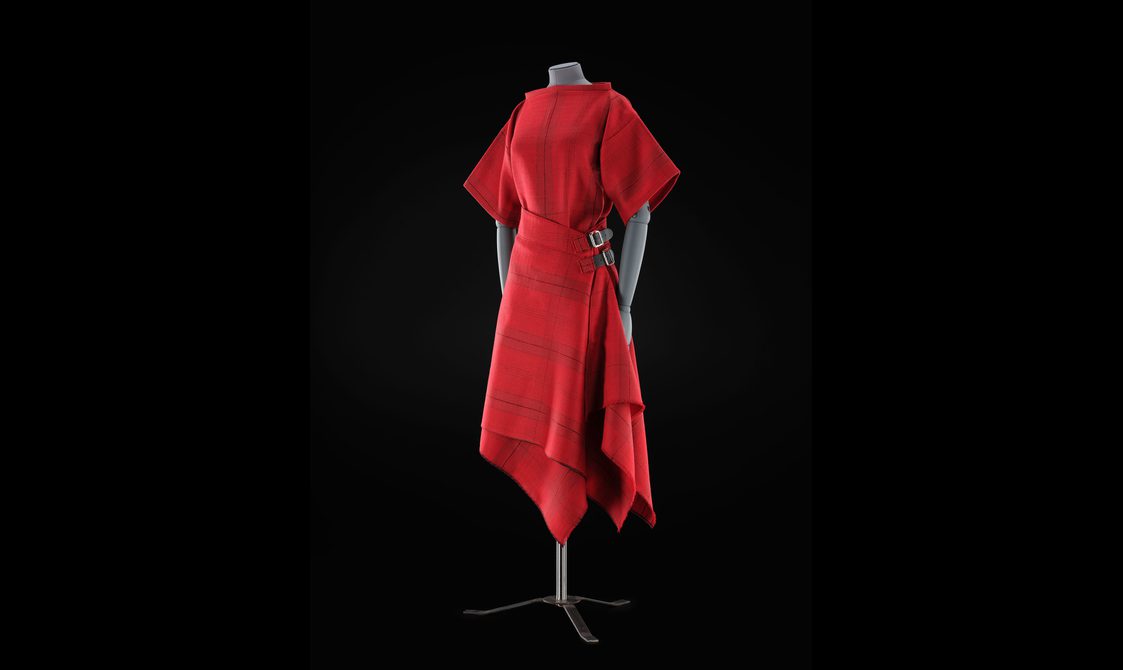 A mannequin wearing a red top and red kilt skirt with a subtle tartan pattern