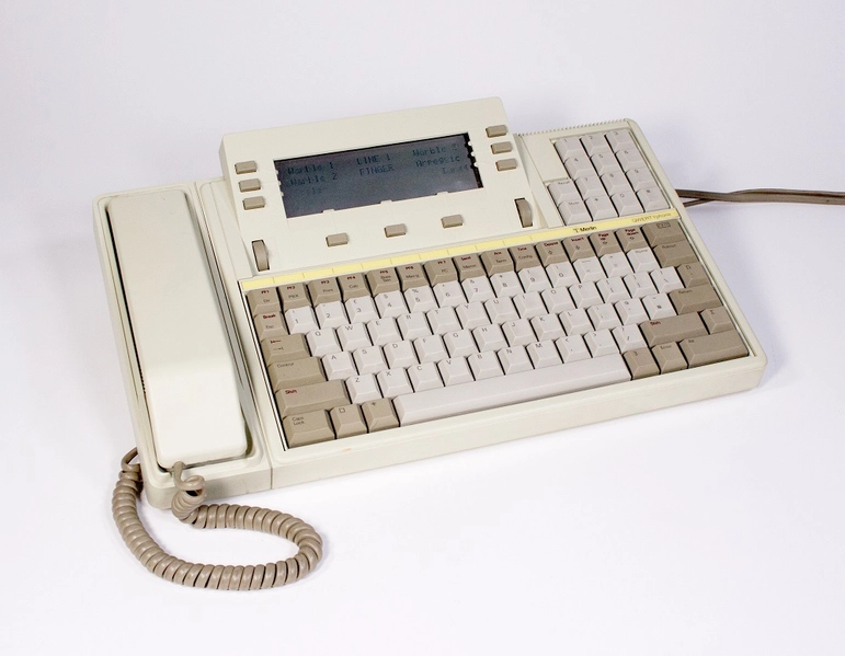 A cream telephone, with a receiver on one side and a keyboard on the other. A small screen sits above the keyboard.