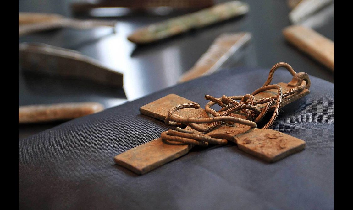 A rusted metal cross on a black cushion.