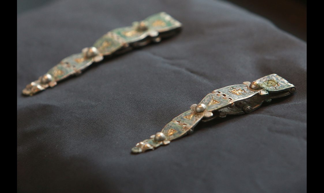 Two silver hinged straps on a black cushion